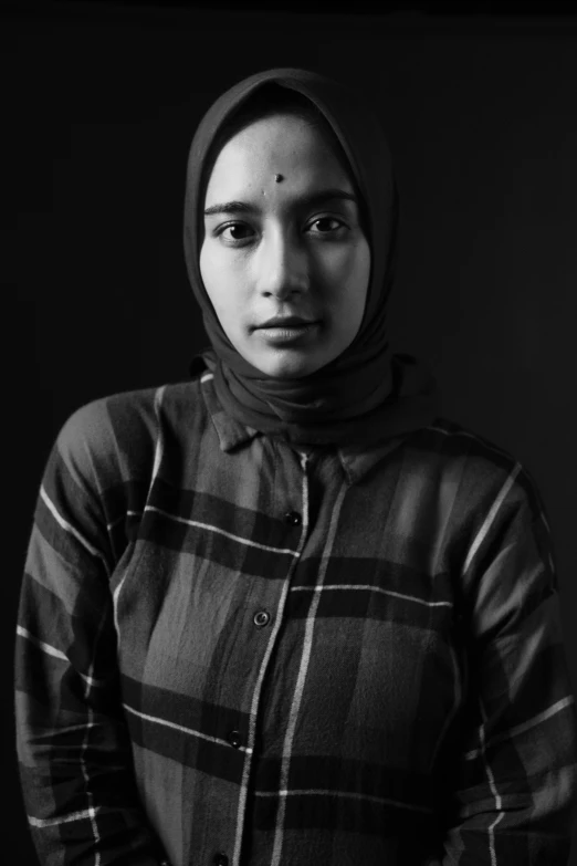 a woman in a hijab stands looking up to the camera