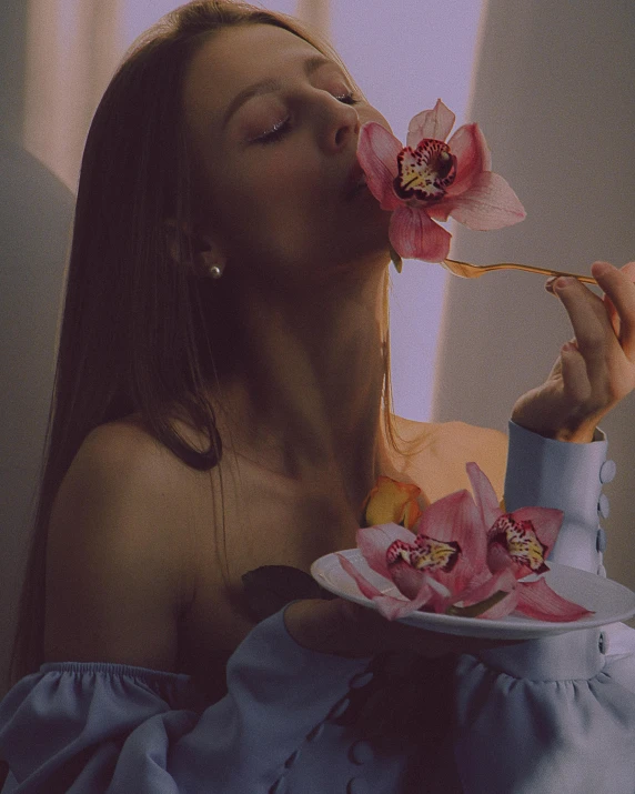 a woman biting into a flower that has been placed on a plate