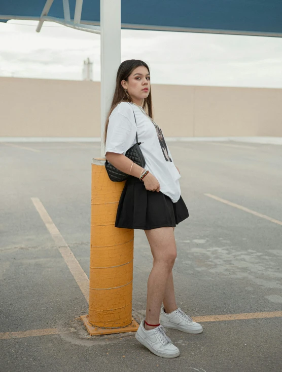 a girl standing near a pole posing for the camera