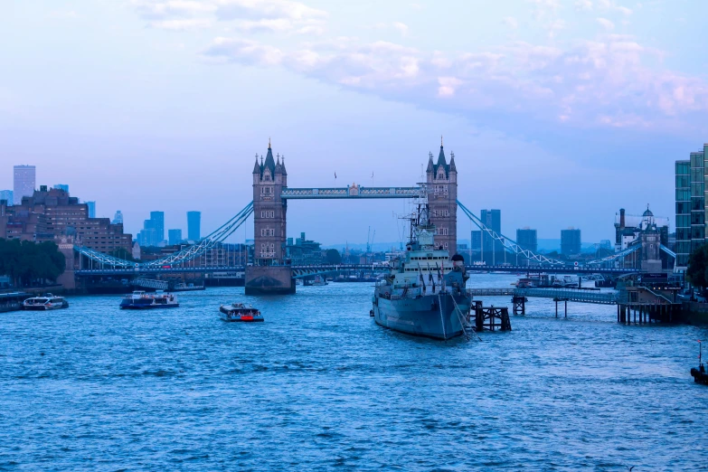 boats are in the water with a bridge and buildings in the background