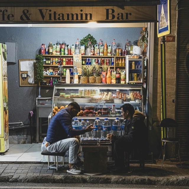 two people sit at a counter outside of a food and beverage store