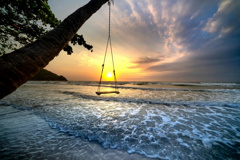 a person is on a swing suspended above the ocean