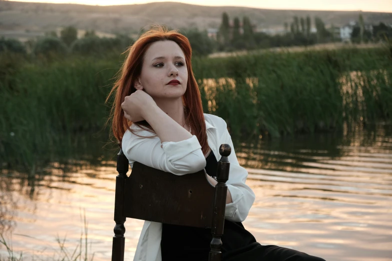 a woman sitting on a chair next to water