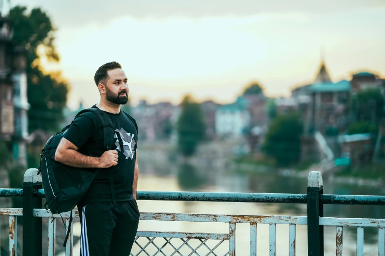 the man is leaning on the fence while standing