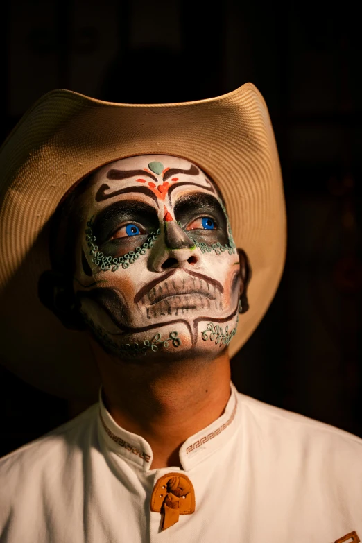 a man in white shirt and cowboy hat with face painted in a skull