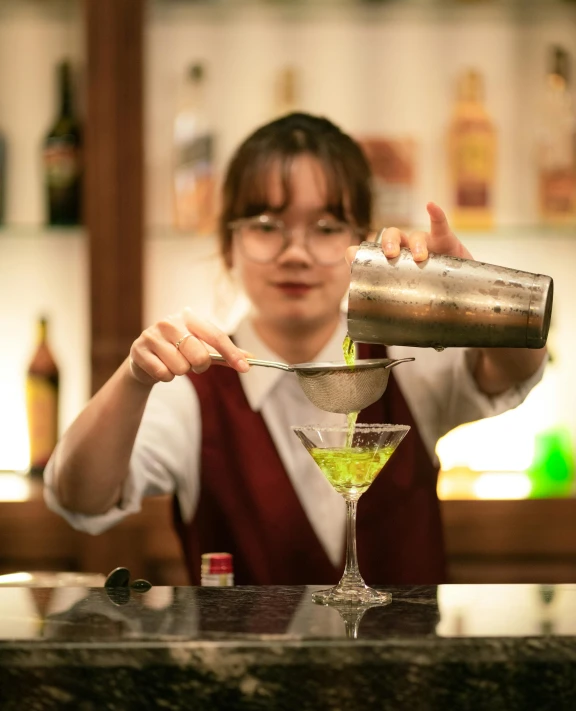 a woman in a bar pouring drinks into a martini glass