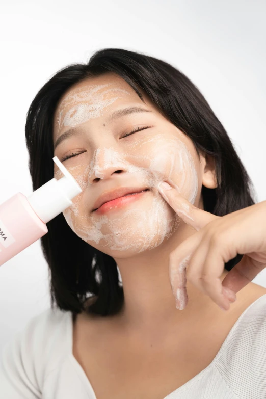 a girl putting face mask on her face and applying it with it