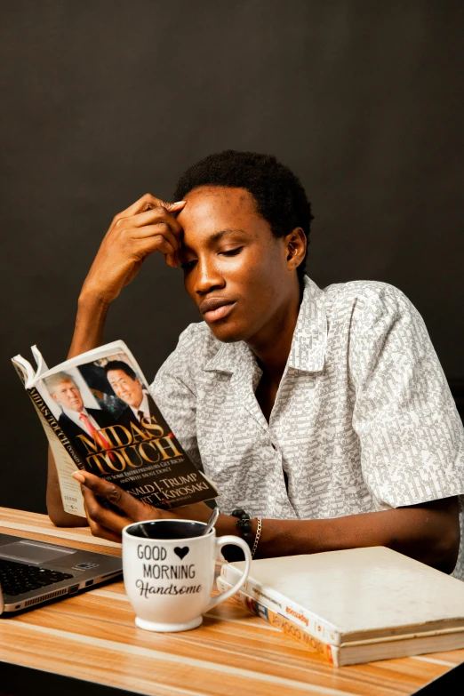 a woman is sitting at a table reading the magazine