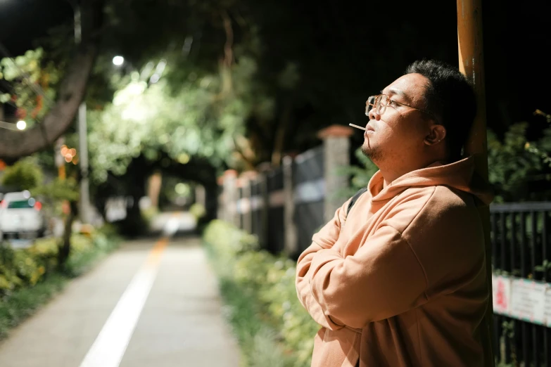 an older man smoking a cigarette while standing on the side of the road