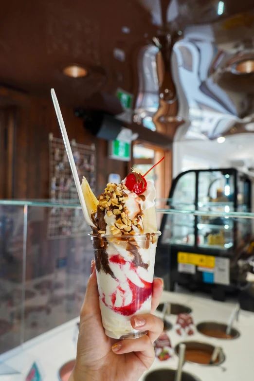 someone holding up a gelato and chocolate sundae