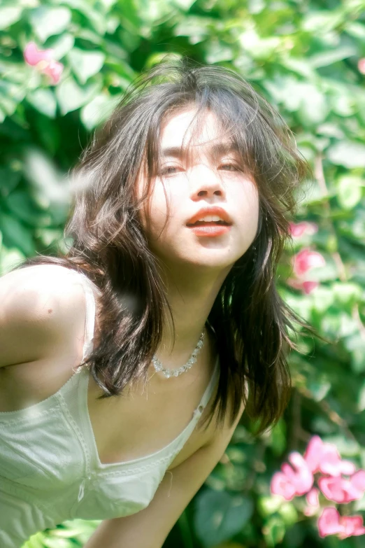 a young woman in white top sitting next to green plants