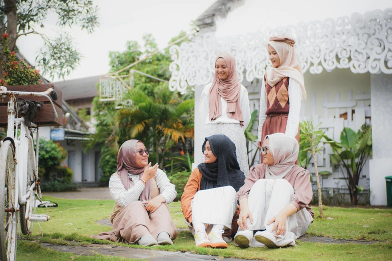 five women dressed in ethnic clothing sitting on the ground