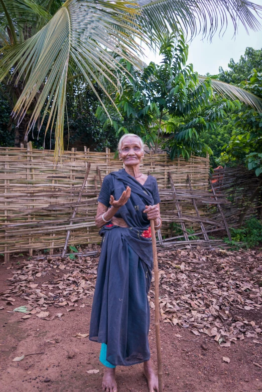 woman sitting in the dirt holding a stick and smiling