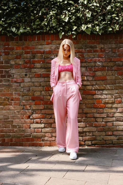 a woman wearing pink pants standing in front of a brick wall