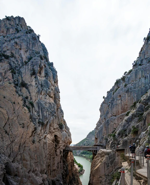 people are riding on the walkway between two huge mountains