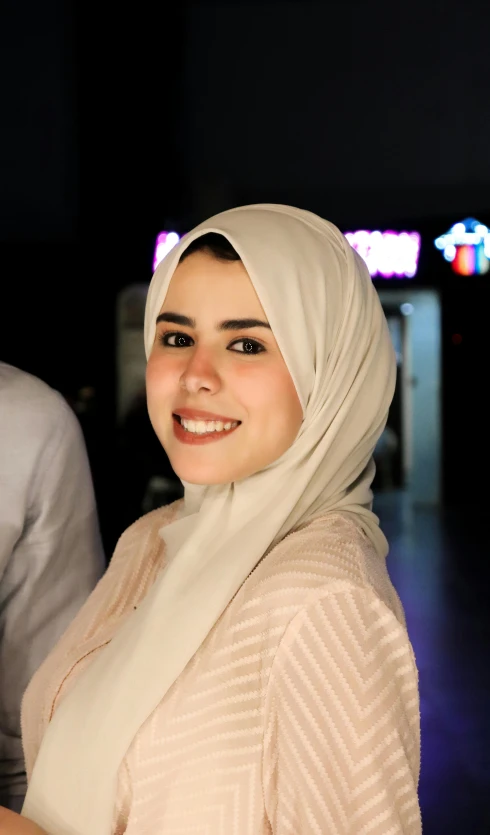 a woman wearing a hijab smiles for the camera