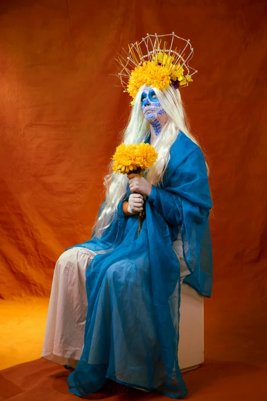 a white and blue man with orange flowers sits in a po studio