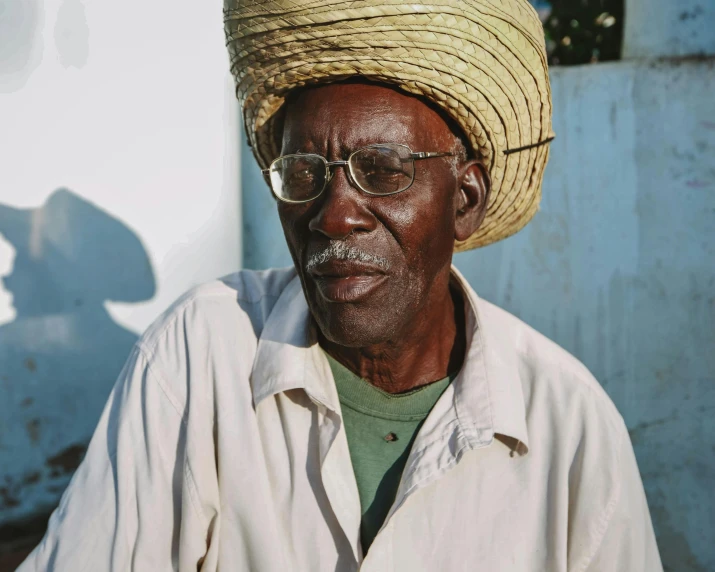 an older man wears a straw hat and glasses