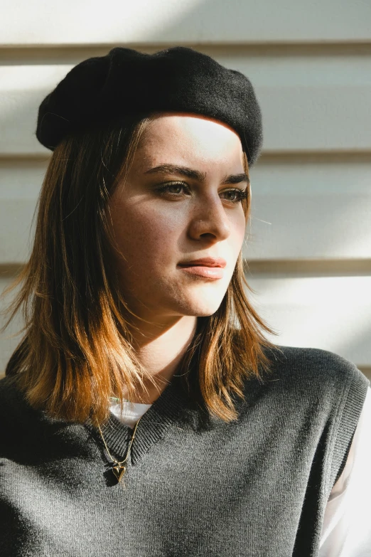 a young woman wearing a gray sweater and black cap