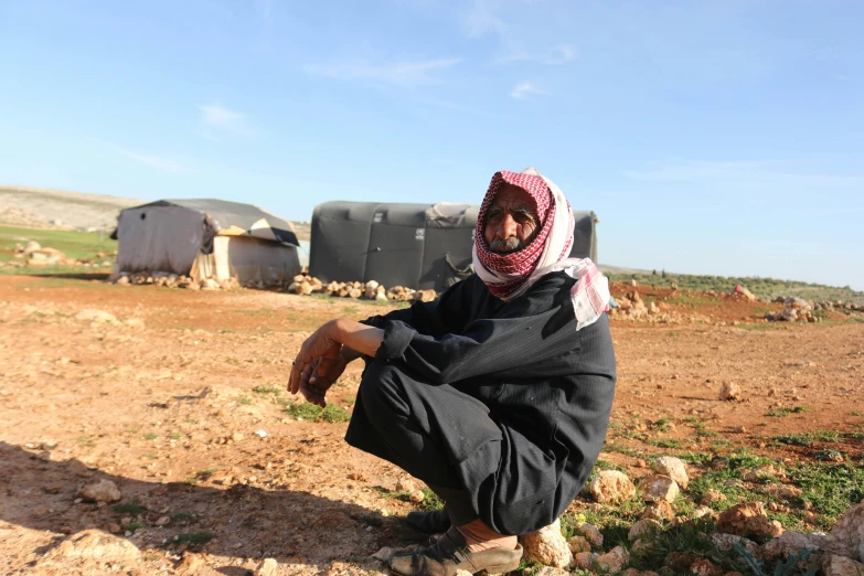 a woman sitting down on the ground in front of a cow pen