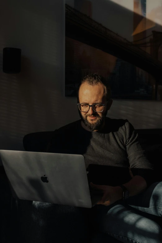 man with beard wearing glasses using his laptop