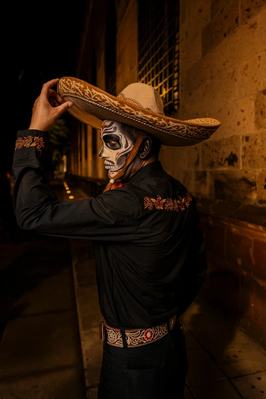 man with painted skull and face paint holding hat