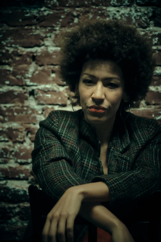 a woman sitting next to a brick wall