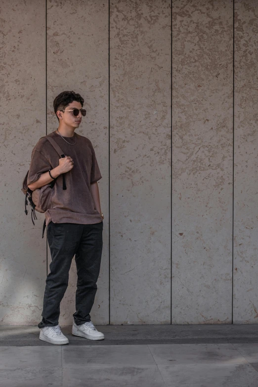 a boy standing on a sidewalk next to a cement wall