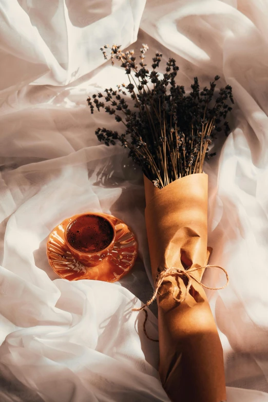 a vase filled with dried flowers next to an old piece of cloth