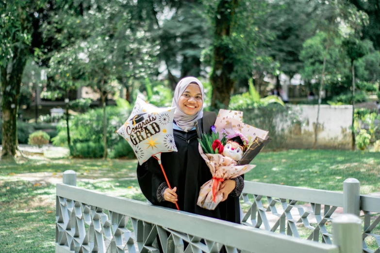 a woman is standing on a bridge holding flowers and a sign