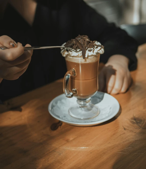 a person sitting at a wooden table with a coffee cup