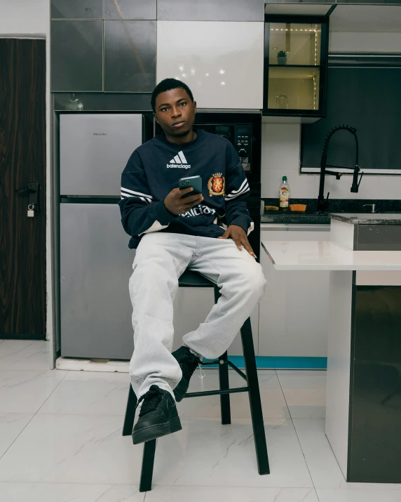 there is a man sitting on top of a chair in the kitchen