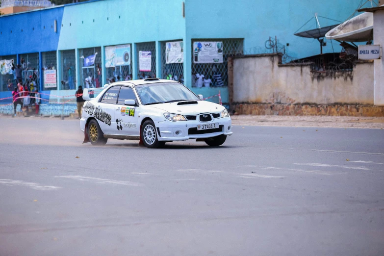 a small white car on a street in the rain