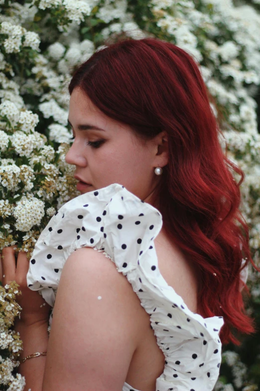 a lady with long red hair and white dress in the wild flowers