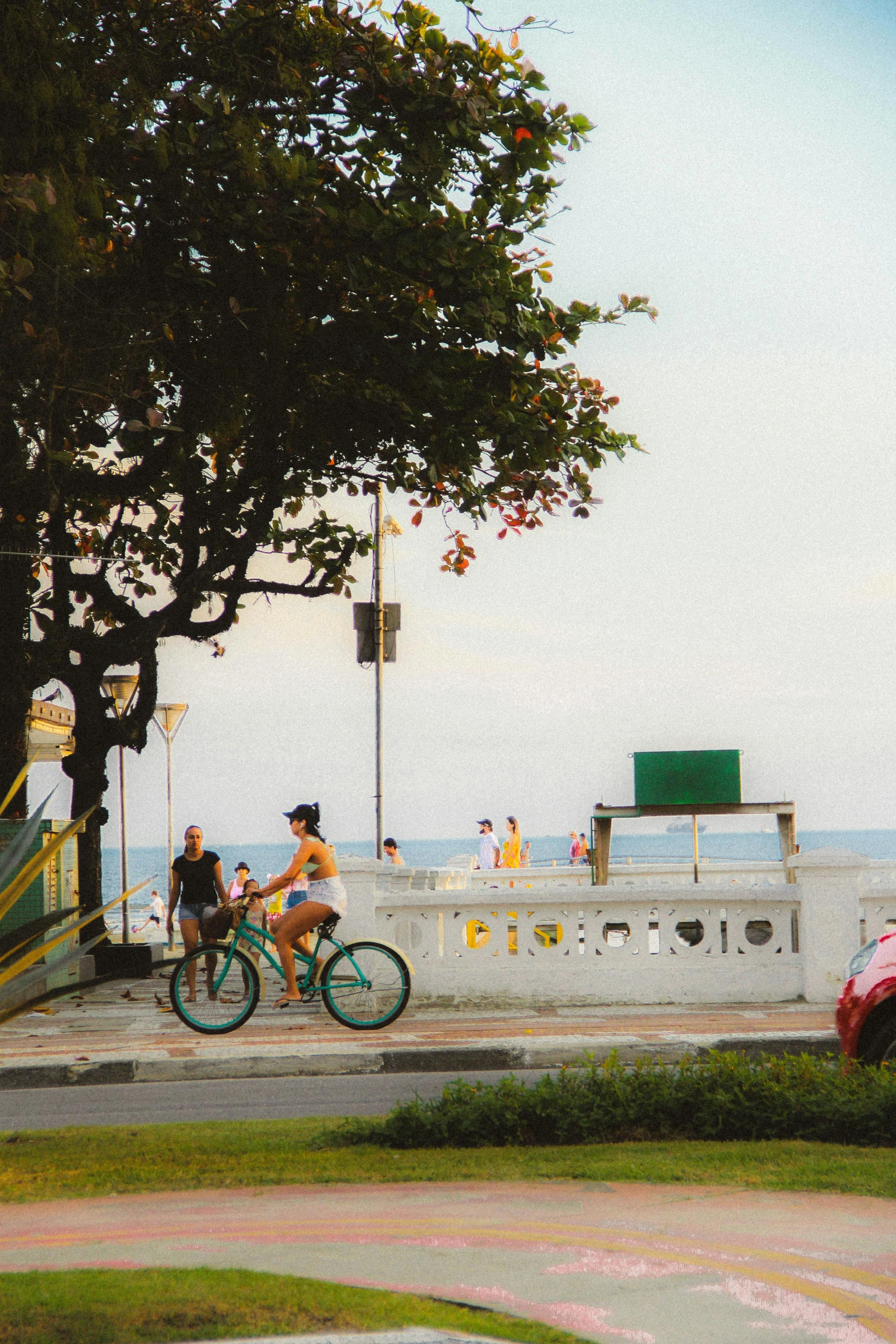 people are riding bicycles on the sidewalk near a lake