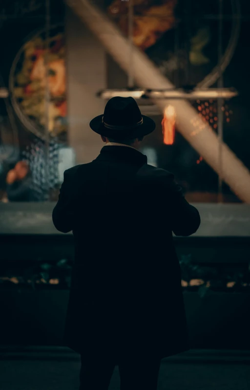 silhouette of man wearing a hat looking down at street