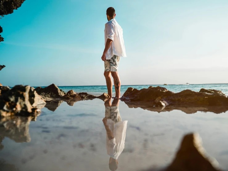 a man looking out on the ocean while holding onto a white jacket