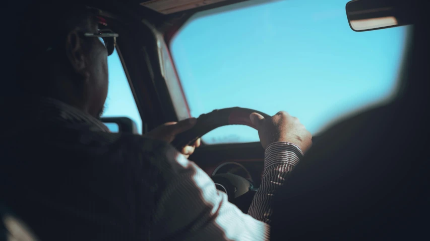 a man driving a car with a driver's seat up and a camera on the dashboard