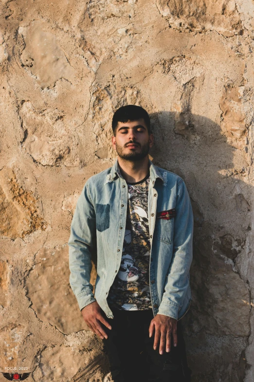 a man standing by a stone wall posing for the camera