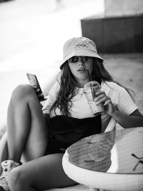 a girl sitting on a blanket holding a cell phone