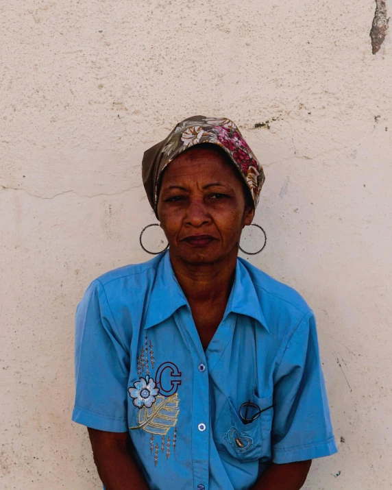 a woman with head scarf standing against a white wall