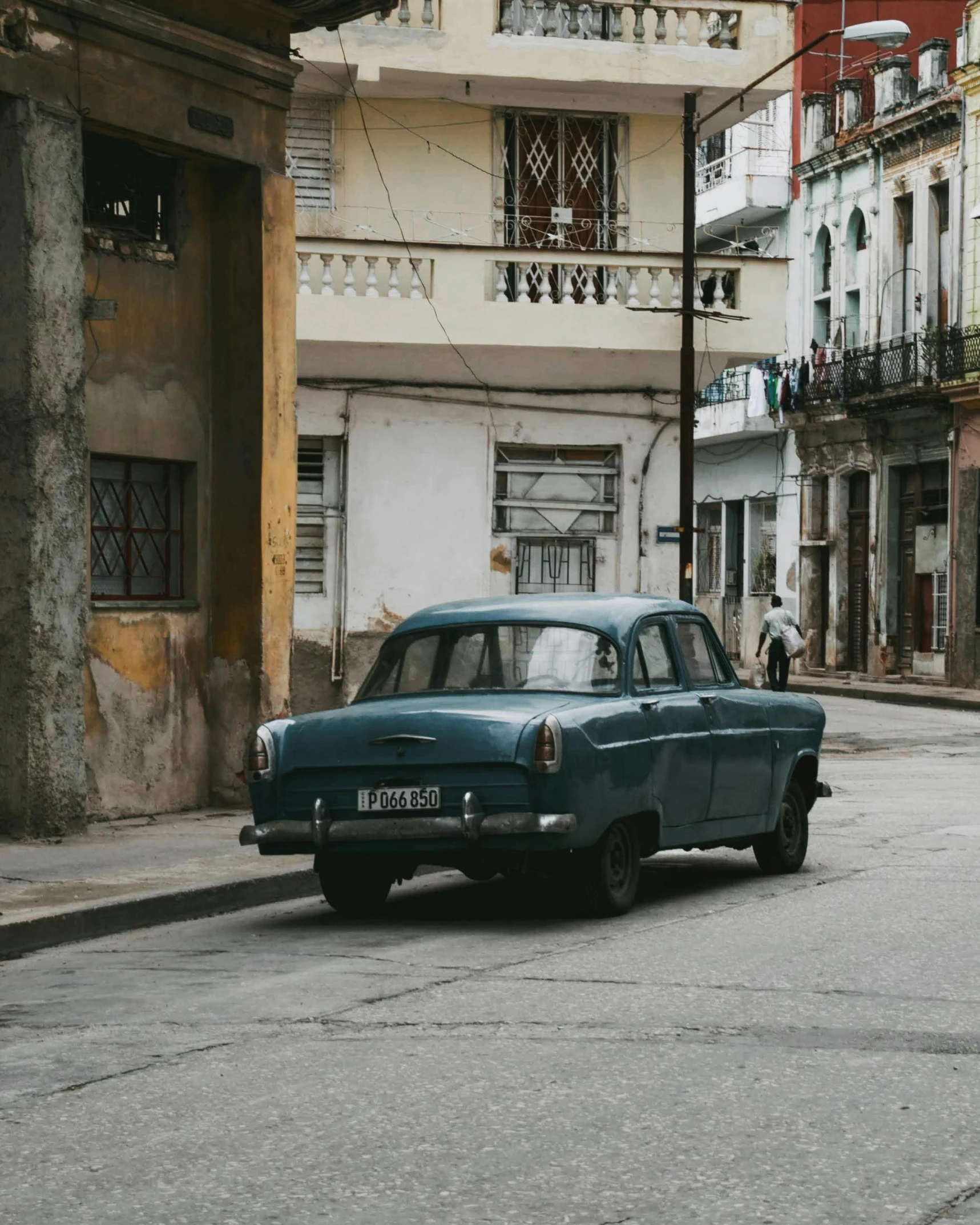 the old car is parked on the street near the buildings