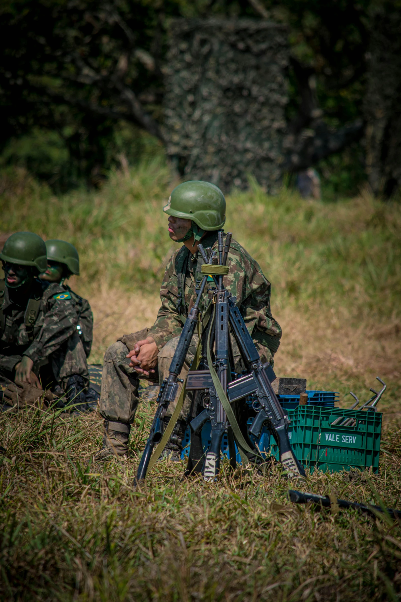 three men in army uniforms look through a scope