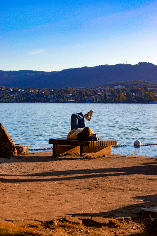 a man is sitting on a bench next to the water