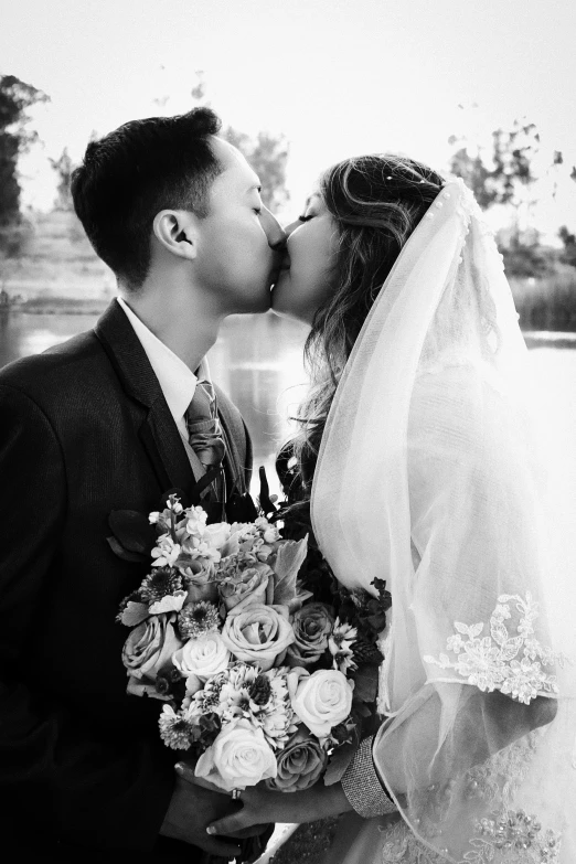 a bride and groom kissing in black and white