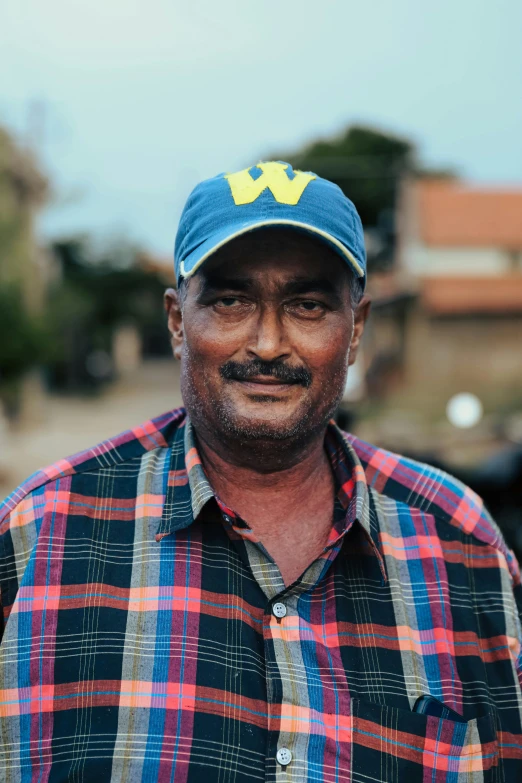 a black man with a beard and plaid shirt looking straight ahead