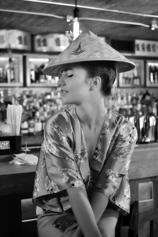 a woman with a hat sitting at the bar