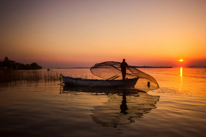 a fisherman casts his nets on the lake