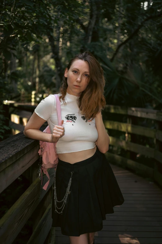 a woman standing on a bridge with a pink purse