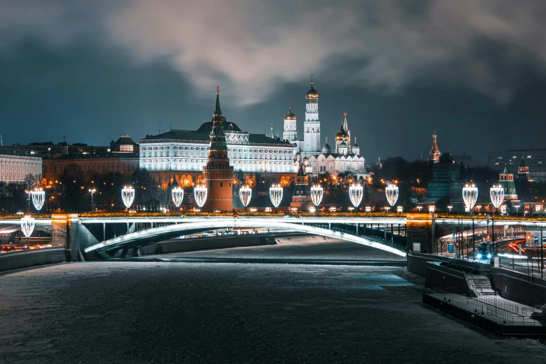 a city at night with a light rail and river with lights in front of it